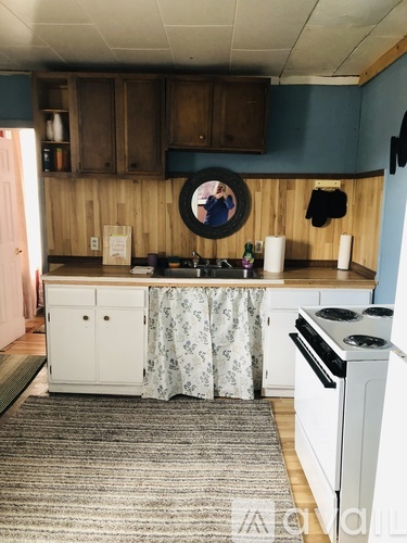 A kitchen with a white stove and a round mirror on the wall.