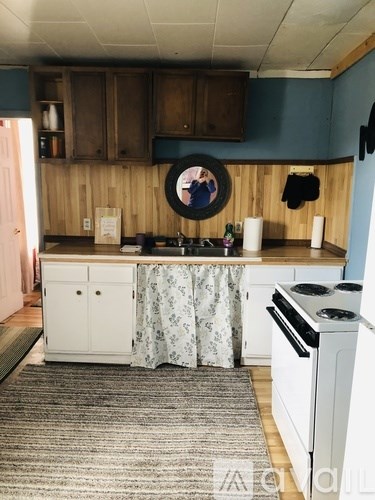 A kitchen with a white stove and a round mirror on the wall.