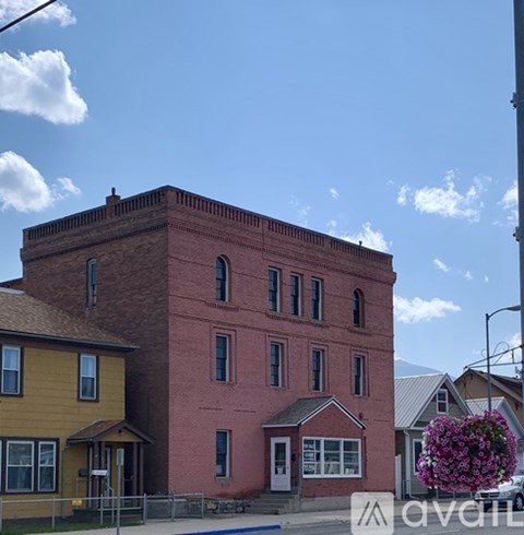 A red brick building with a yellow house in front of it.