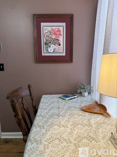 A bedroom with a bed, chair, and a framed picture on the wall.