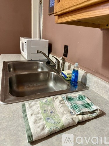 A kitchen sink with a green towel underneath it.