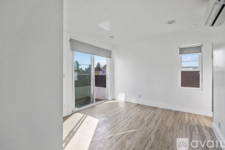 A room with wooden flooring and a window overlooking a building.