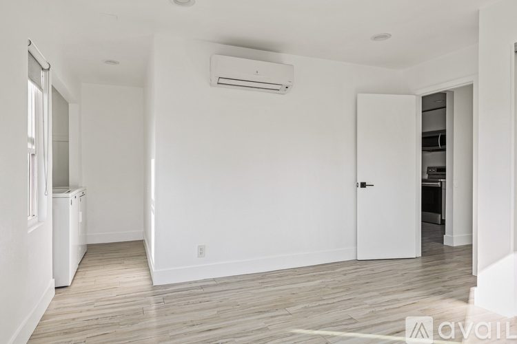 A spacious room with a white door and a window on the left.