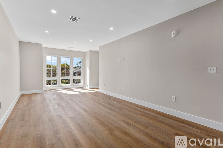 A spacious room with wooden flooring and a large window.