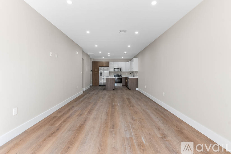A long, empty hallway with wooden floors and white walls.