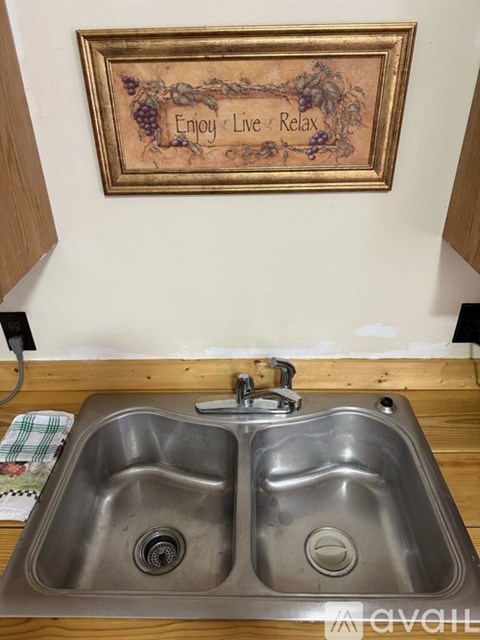 A kitchen sink with a picture frame above it that says Enjoy Live Relax.