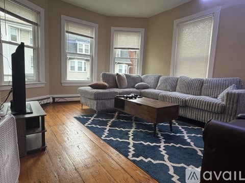 A living room with a grey couch, a wooden coffee table, and a television.