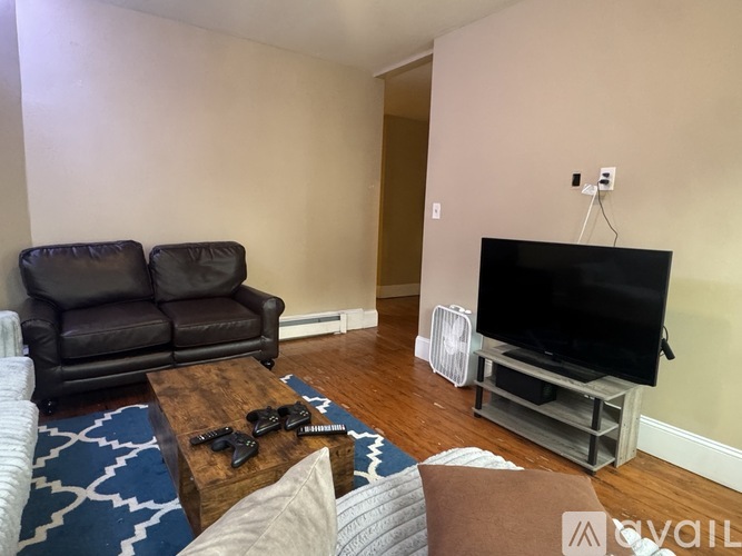 A living room with a brown leather couch, a wooden coffee table, and a flat screen TV.