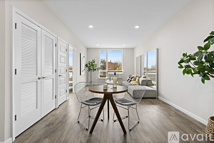 A dining room with a table set for four and a couch in the background.