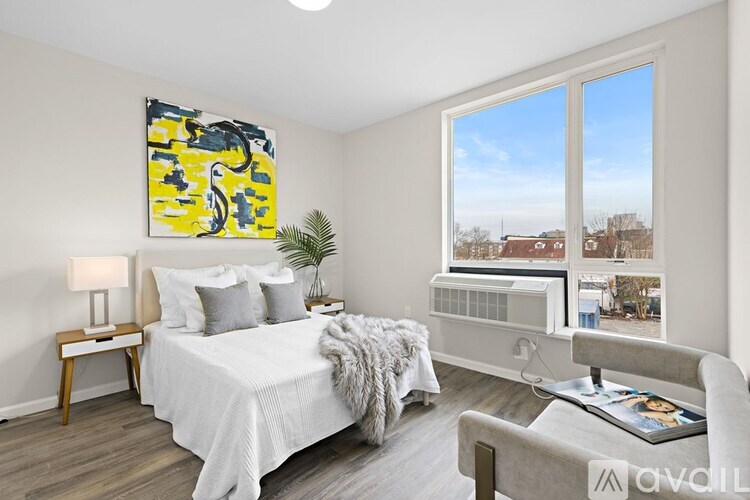 A bedroom with a bed, chair, and a painting on the wall.