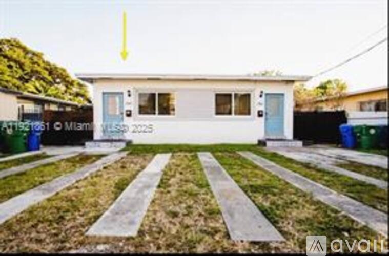 A small white house with a blue door is for sale in Miami.