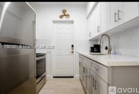 A kitchen with white cabinets and a white door in the background.