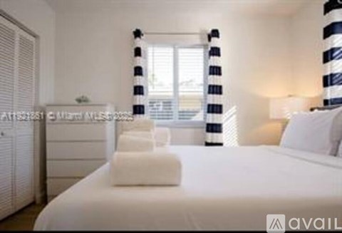 A bedroom with a large bed and striped curtains.