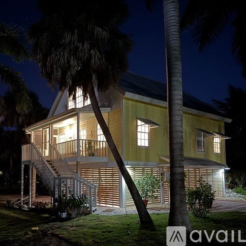 A house with a balcony and a staircase is illuminated at night.