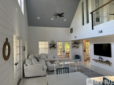 A modern living room with white furniture and a flat screen TV.