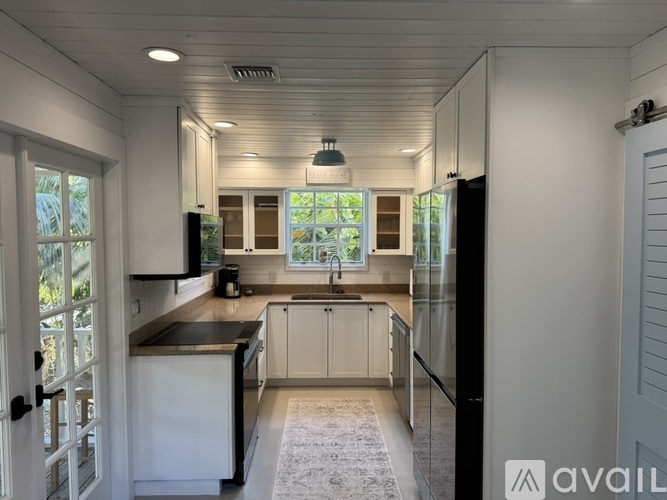 A kitchen with white cabinets and a black countertop.