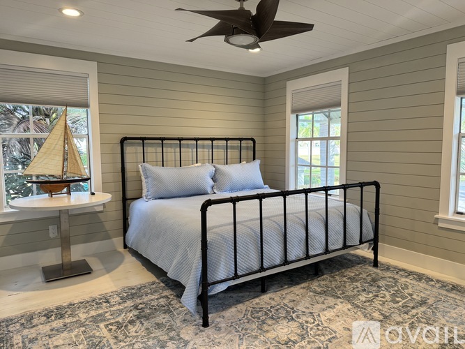 A bedroom with a bed, a sailboat, and a ceiling fan.