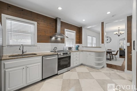 A modern kitchen with white cabinets and a checkered floor.