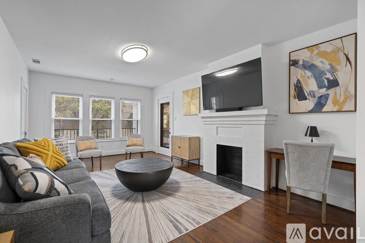 A living room with a grey couch, a fireplace, and a television mounted above it.