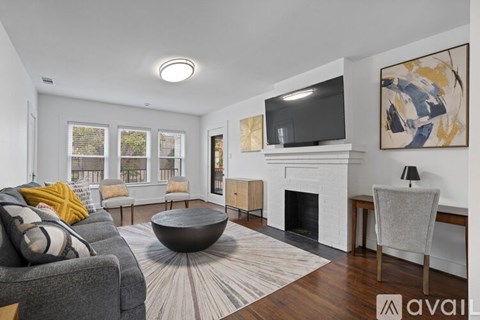 A living room with a grey couch, a fireplace, and a television mounted above it.