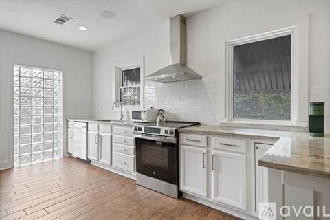A kitchen with white cabinets and a wooden floor.