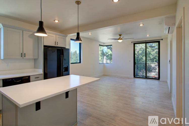 A modern kitchen with white countertops and a black refrigerator.