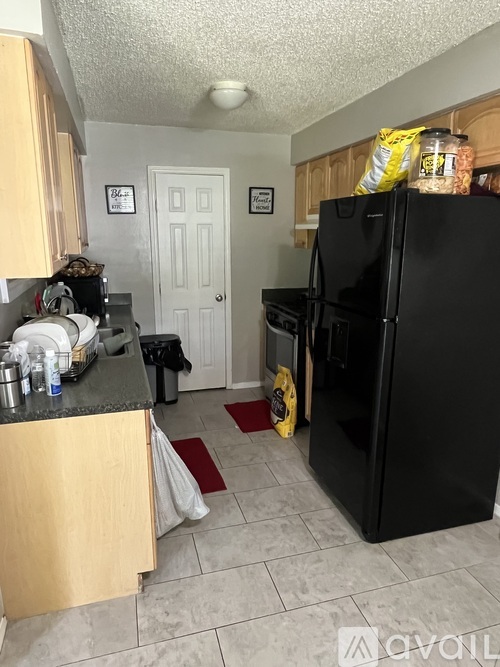 A kitchen with a black fridge and a white door.