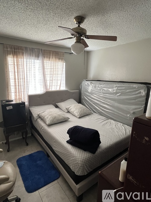 A bedroom with a bed, a ceiling fan, and a chair.