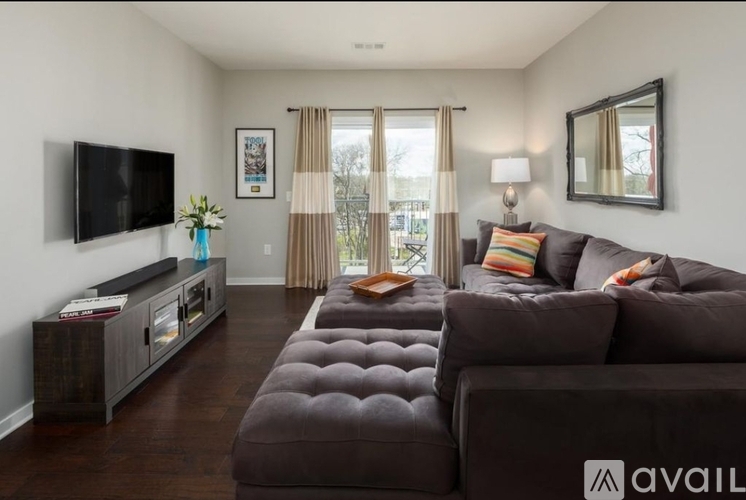 A living room with a brown couch and a television on the wall.