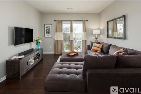 A living room with a brown couch and a television on the wall.