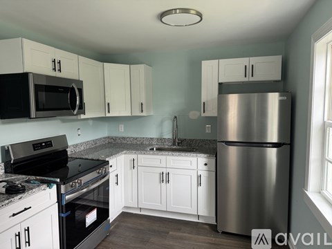 A kitchen with white cabinets and a stainless steel refrigerator.