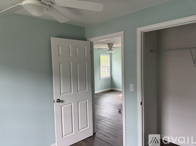 A room with a white door and a ceiling fan.