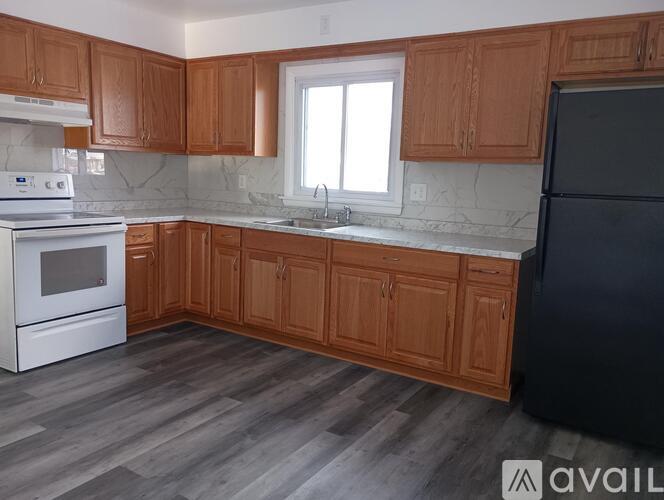 A kitchen with wooden cabinets and a black refrigerator.