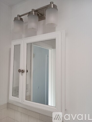 A white cabinet with a mirror and lights above it.