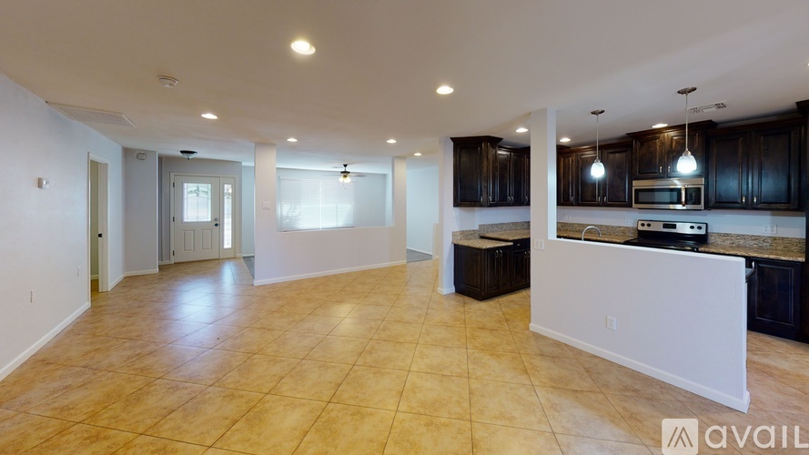 A spacious living room with a kitchen area in the background.