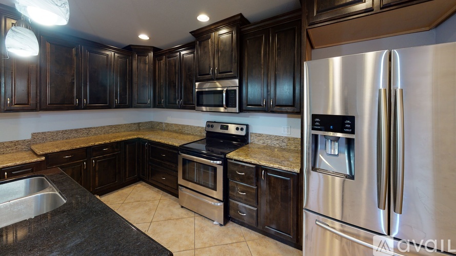 A modern kitchen with dark wood cabinets and stainless steel appliances.