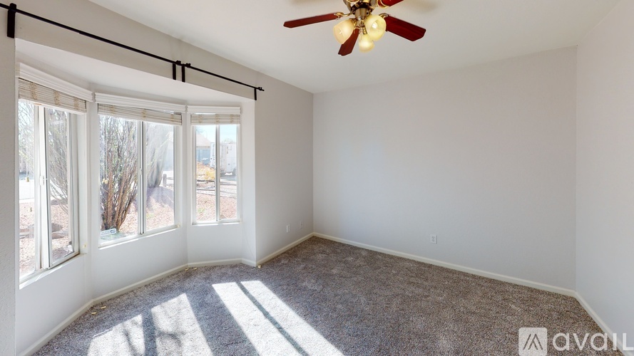 A room with a ceiling fan and sliding glass doors.