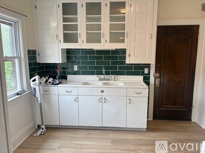 A kitchen with white cabinets and a green backsplash.