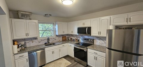 A kitchen with white cabinets and a stainless steel refrigerator.
