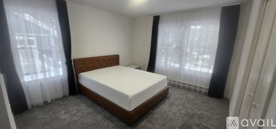 A bedroom with a large bed and a window with curtains.