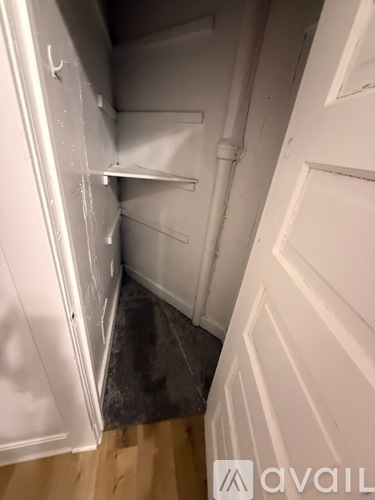 A white door with a shelf and a pipe running along the wall.