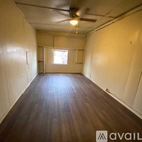 A room with white cupboards and brown flooring.