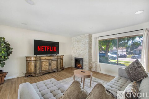 A living room with a large couch, a fireplace, and a Netflix sign on the wall.