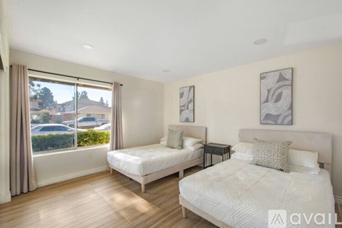 A bedroom with two beds and a large window with a view of the outside.