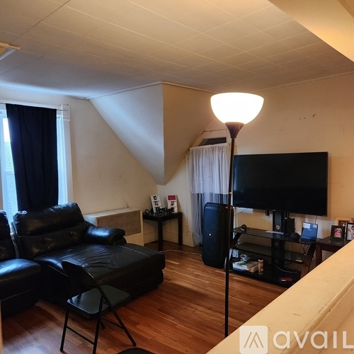 A living room with a black leather couch and a television.