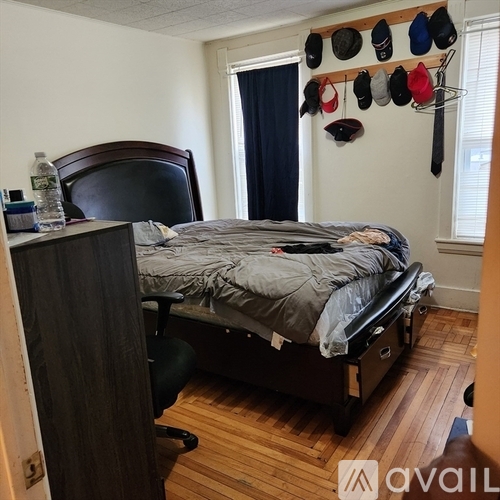 A bedroom with a bed, chair, and a wall-mounted hat rack.