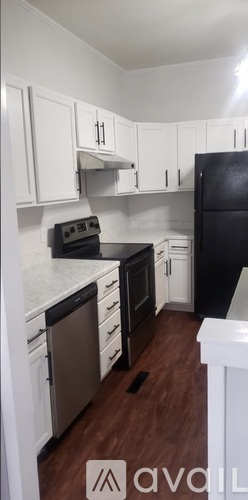 A kitchen with white cabinets and a black fridge.