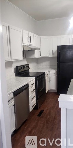 A kitchen with white cabinets and a black fridge.