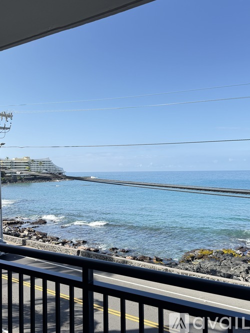 A view from a balcony overlooking a rocky shoreline and a large body of water.