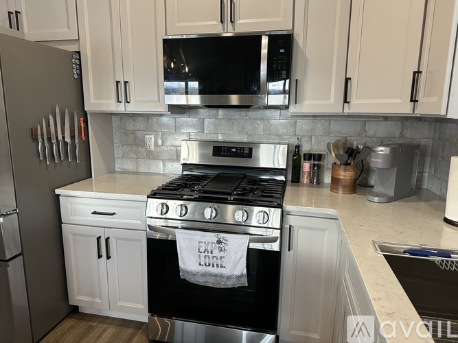 A kitchen with a white stove top oven and white cabinets.